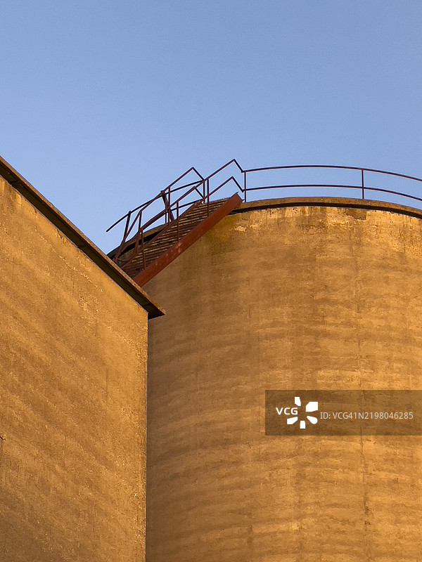 老旧的粮仓塔与生锈的连接楼梯和蓝天图片素材