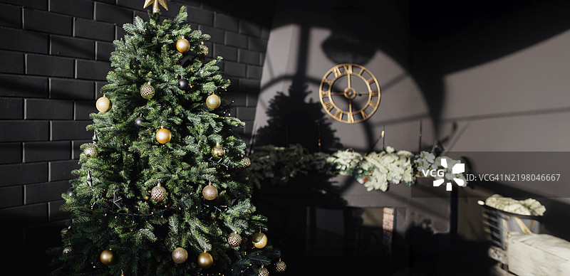 装饰着金色饰品的圣诞树，置于昏暗的房间里，墙上挂着时钟，四周投射出阴影。图片素材