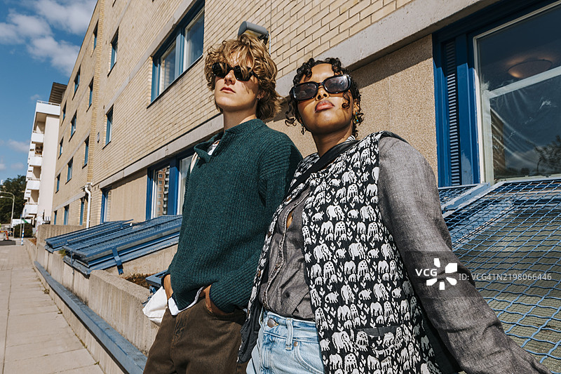 时尚的年轻男女学生在大学校园里戴着太阳镜摆姿势图片素材