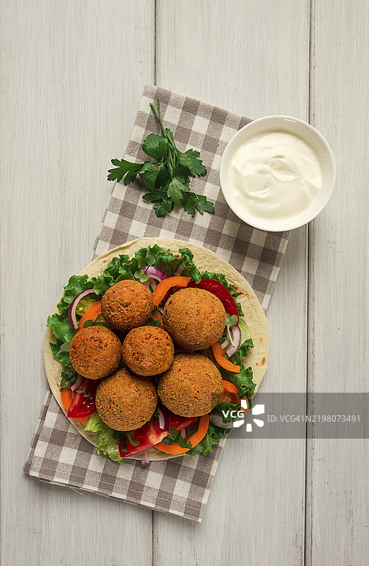 玉米饼包裹的法拉费球，搭配新鲜蔬菜，素食健康食品，背景为白色木纹，无人，选择性对焦图片素材