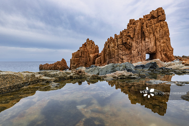 阿尔巴塔克斯的红岩在潮池中倒影，意大利撒丁岛奥利亚斯特拉的托尔图利。图片素材