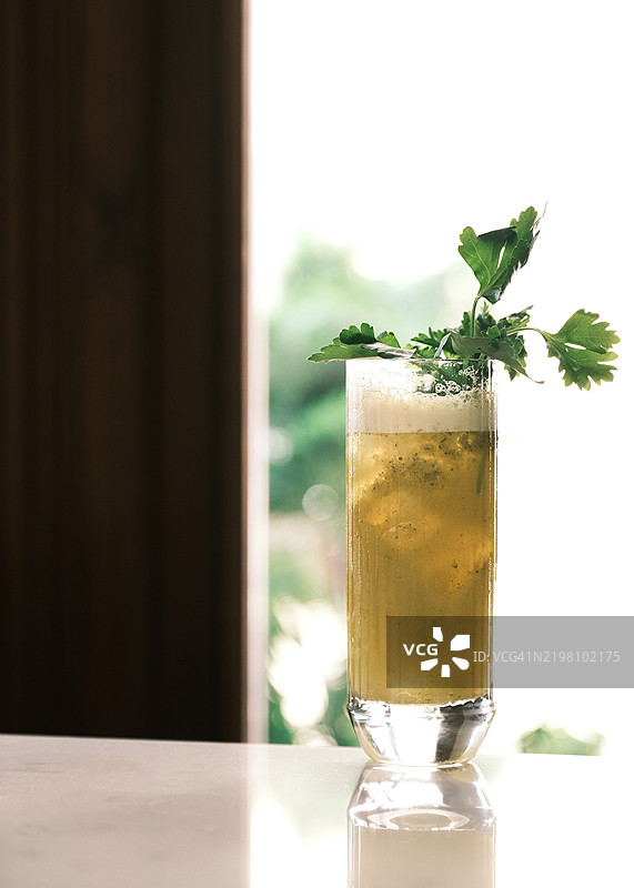 金色意大利鸡尾酒，搭配新鲜香草装饰，盛在高脚杯中，清爽的夏季饮品，供应于明亮的意大利餐厅，优雅的调酒与精致餐饮概念图片素材