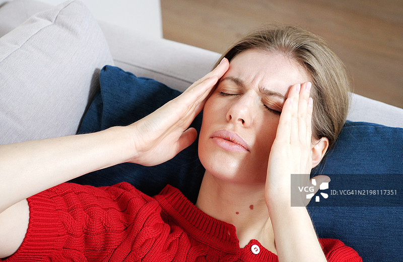 感到压力的年轻金发女性双手抱头，正在经历偏头痛。心理压力与疼痛概念视频图片素材