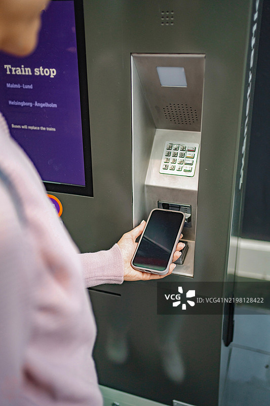 在火车票机前使用手机的人图片素材