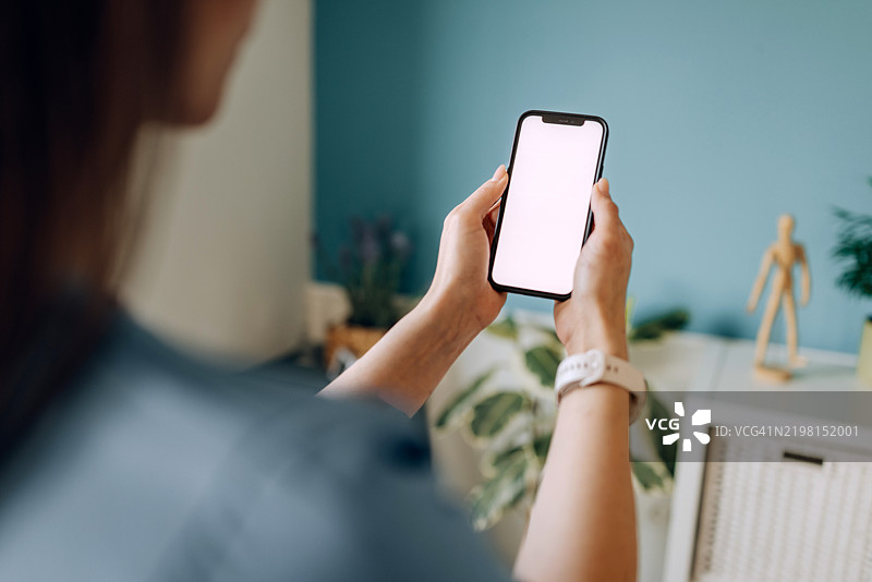 女性护士肩后视角，手持白屏智能手机图片素材