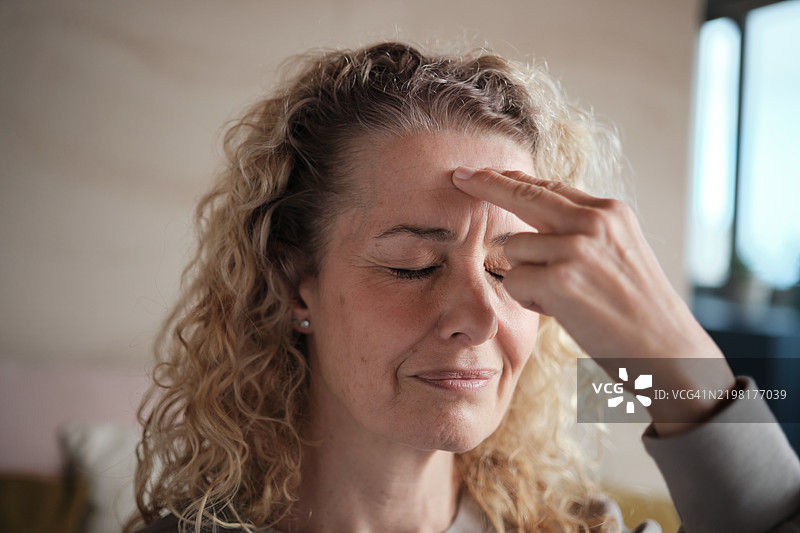 女性练习情绪释放技巧（EFT）以缓解压力、焦虑或疼痛，手指轻触额头，双眼闭合。图片素材