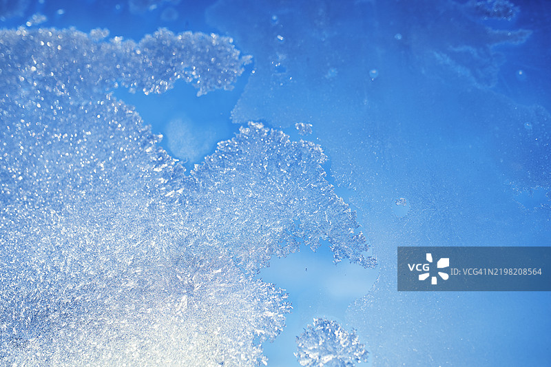 窗户上的霜晶体特写，背景是明亮的蓝天图片素材