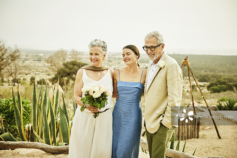 中景拍摄女儿在婚礼后拥抱新婚父母图片素材
