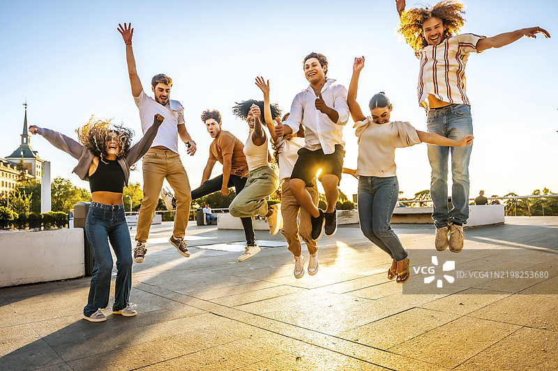 多种族年轻人在日落时分的街道上跳跃玩乐的全身照片图片素材