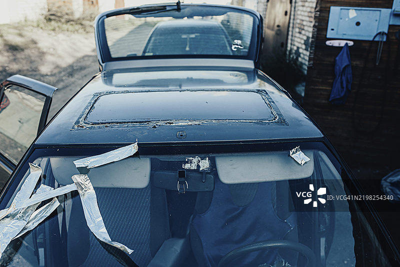 挡风玻璃破损并用胶带固定的汽车，停放在户外图片素材