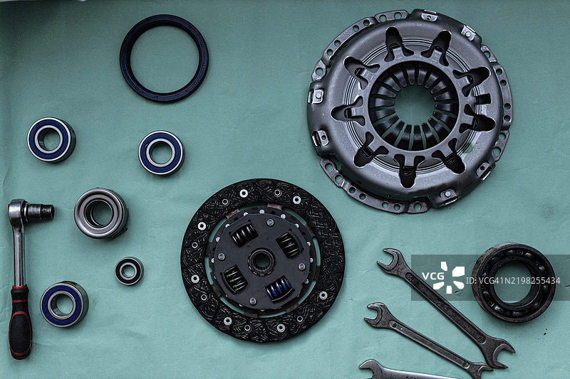 各种汽车零件，包括离合器组件和工具，摆放在绿色表面上图片素材
