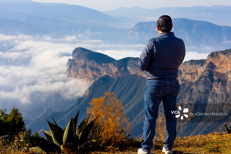男人在山顶享受美景，手里拿着咖啡杯图片素材