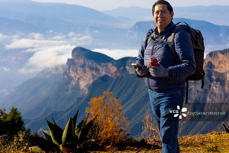 男人在山顶享受美景，手里拿着一瓶水图片素材