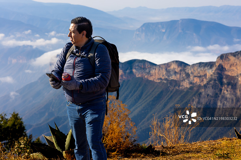 男人在山顶享受美景，手里拿着咖啡杯图片素材