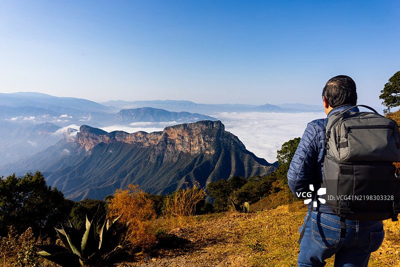男人在山顶享受美景，手里拿着咖啡杯图片素材