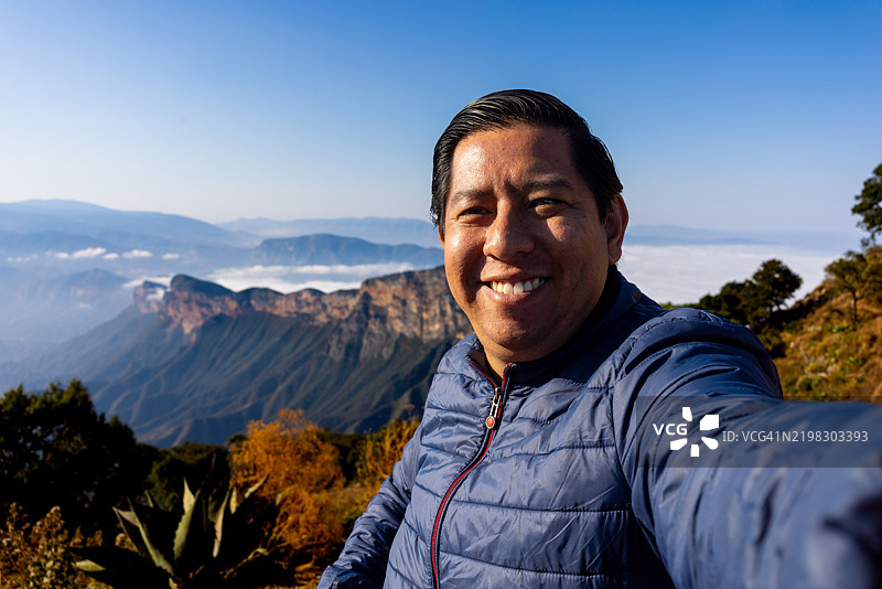 男子在山顶拍摄自拍照，背景是美丽的风景图片素材