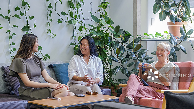 三位多元化的快乐女商人在休息区放松聊天图片素材