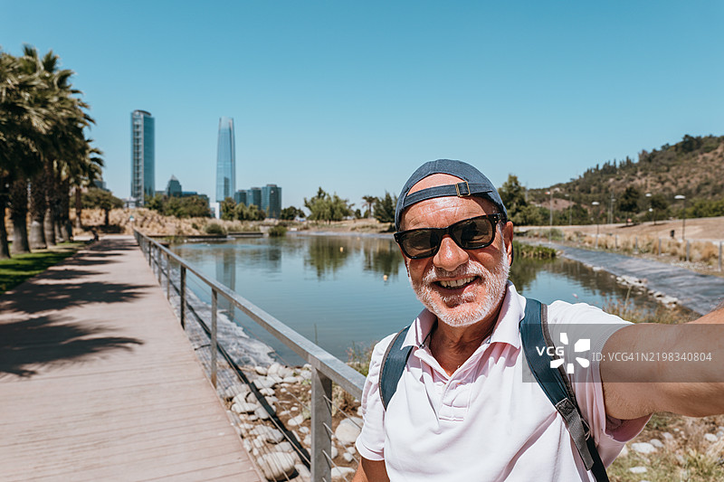 老年人在城市公园里自拍，背景是城市天际线。图片素材