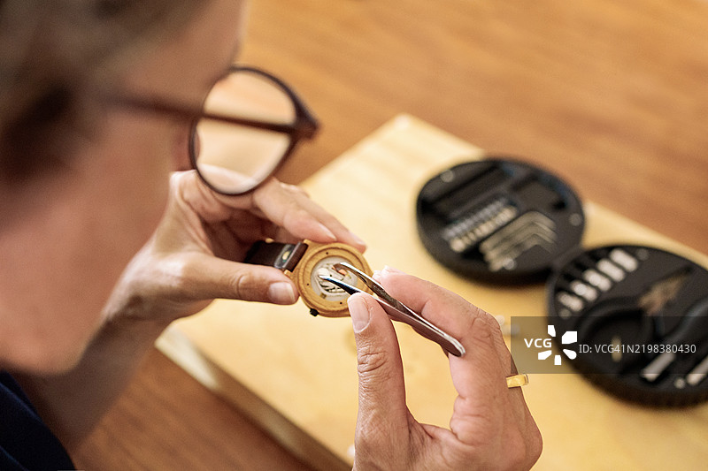女钟表匠在她的工作室里修理手表图片素材