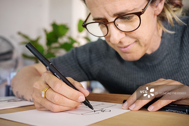 女性在家中用马克笔在素描本上绘画的特写镜头图片素材