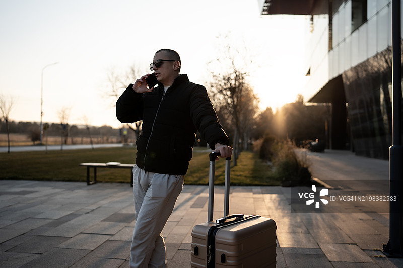 这个男孩在等交通工具时正在打电话。图片素材