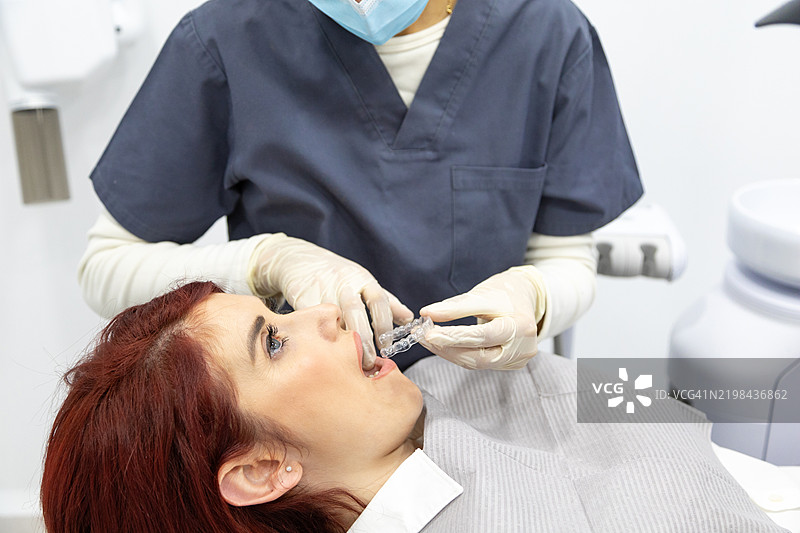 牙医在牙科诊所为女性患者安装隐形矫正器图片素材