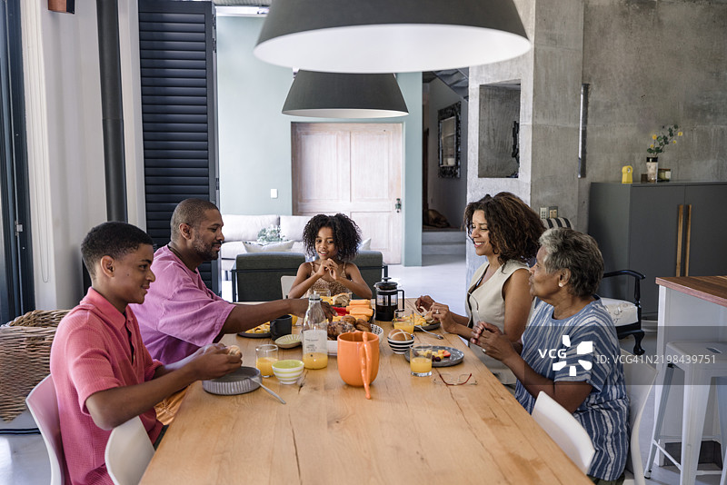父母和两个孩子一起分享愉快的早餐时光。图片素材