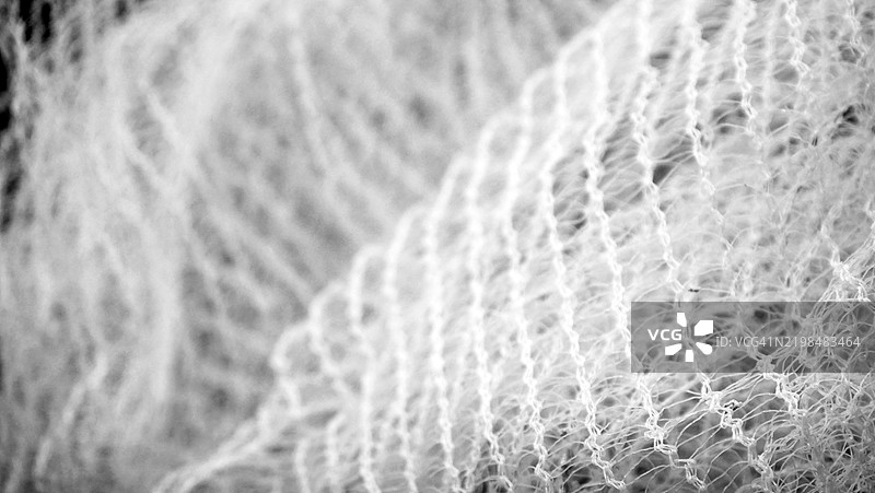 白色尼龙网的大网眼特写。过度曝光的照片。焦点在右前景（角落）。图片素材