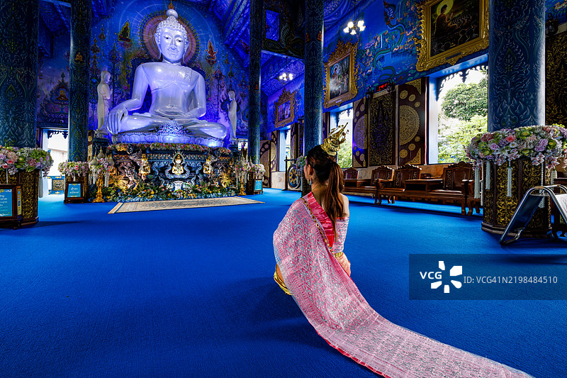 在泰国北部蓝庙跪着的女性。图片素材