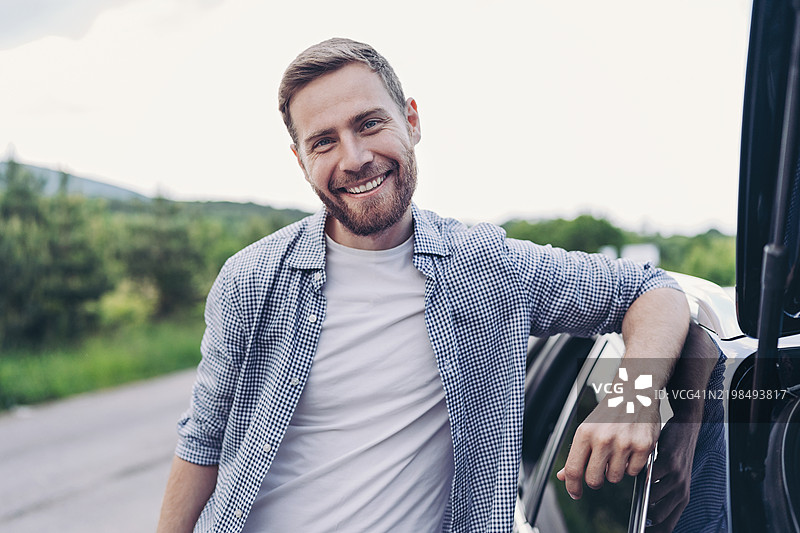 微笑的年轻男子在路上休息的肖像图片素材