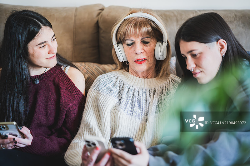 祖母在家中与孙女们一起学习新技术，使用智能手机。图片素材