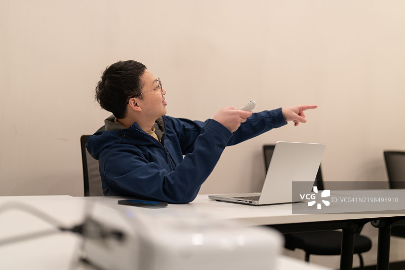 一位亚洲男子在会议室使用投影仪展示电脑上的文件图片素材