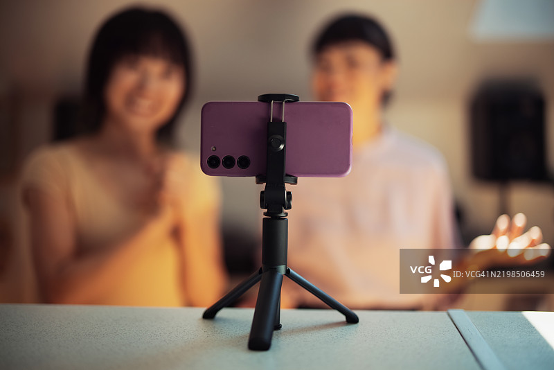 三脚架上的设备录制内容，背景中模糊的人物图片素材