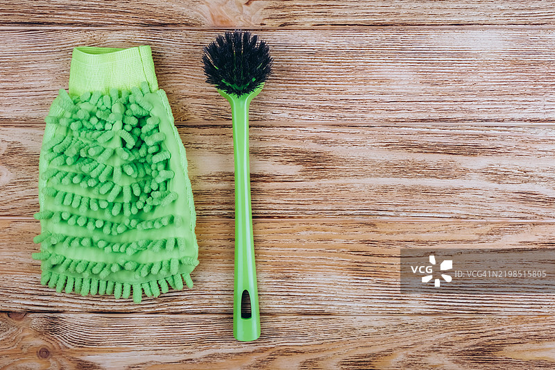 绿色洗碗手套和清洁刷放在木板上。图片素材
