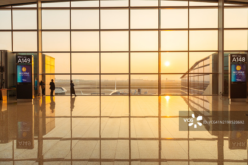 黎明时分，温暖的阳光透过广州机场航站楼高大的落地窗洒在干净整洁的地面上。图片素材