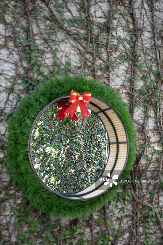 一圈带红色蝴蝶结的花环挂在墙上图片素材