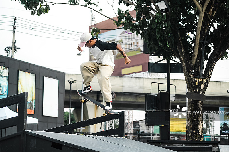 熟练的滑板运动员在城市滑板公园的斜坡上表演特技图片素材