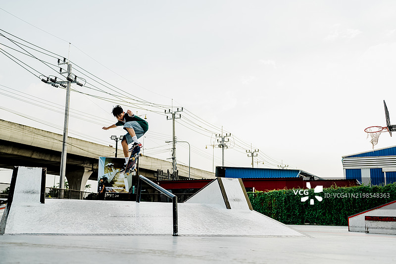 滑板运动员在城市滑板公园的铁轨上表演空中技巧图片素材