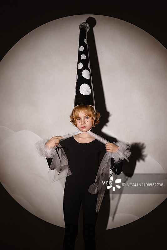 小女孩穿着皮埃罗服装在聚光灯下摆姿势。图片素材