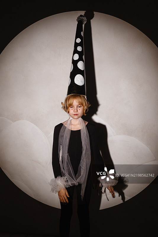小女孩穿着皮埃罗服装在聚光灯下摆姿势。图片素材