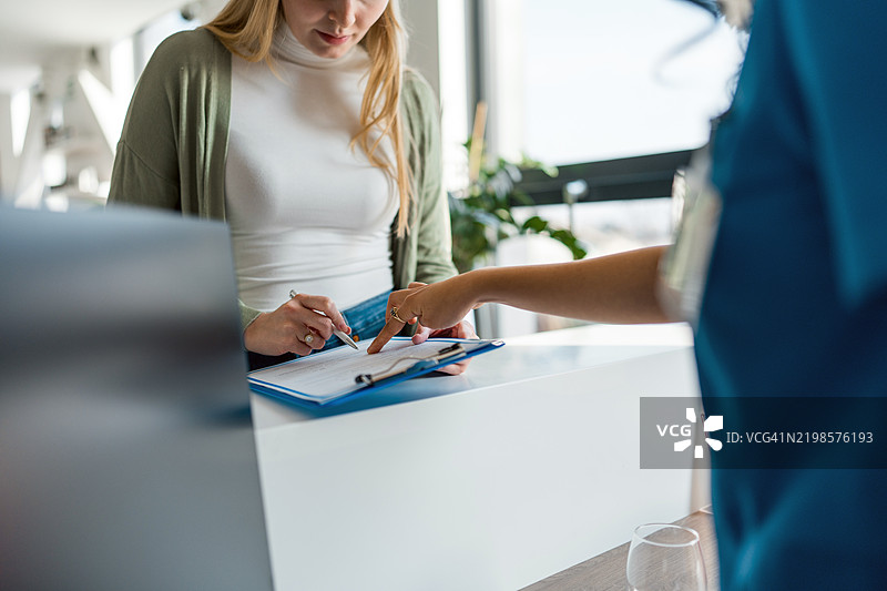 年轻的白人女性在接待处与护士互动图片素材