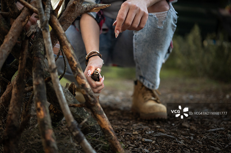 露营者在森林中用打火机点燃篝火图片素材