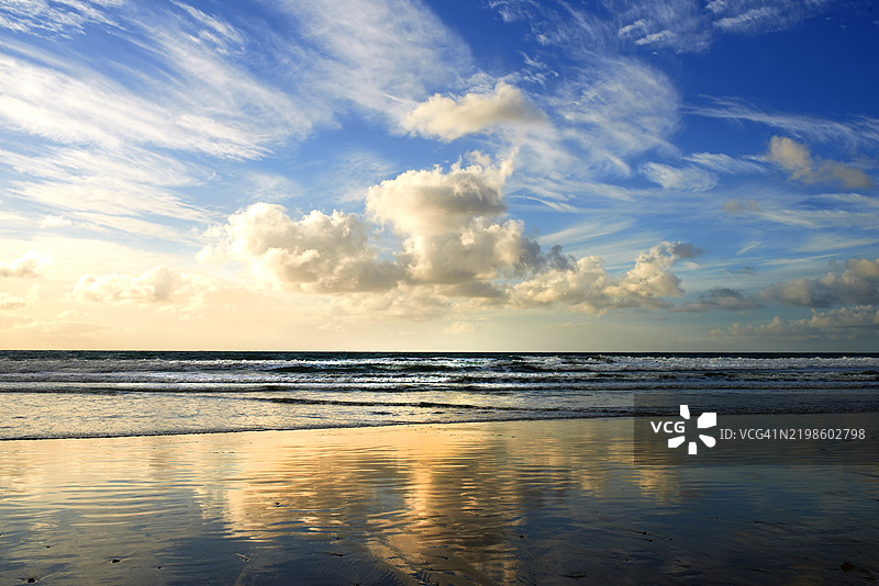 丹麦宁静的海岸日落，展现温柔的波浪和倒影图片素材