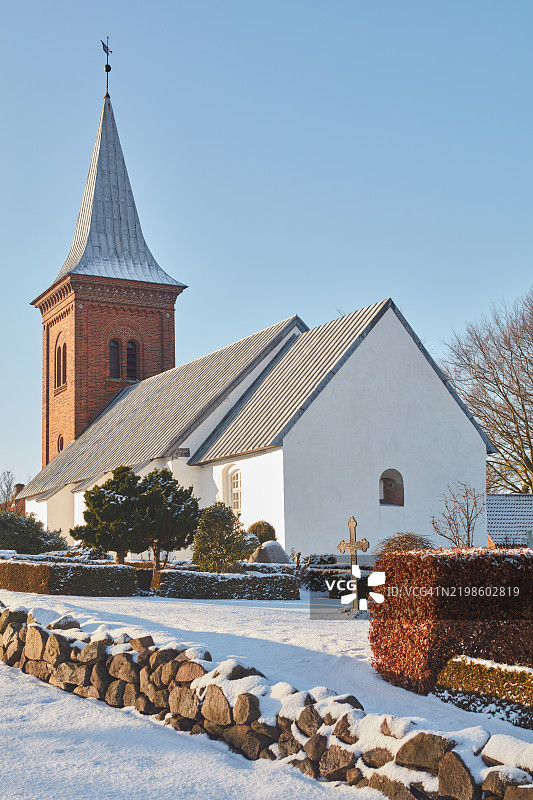 冬季被雪覆盖的传统丹麦教堂与清澈的蓝天图片素材