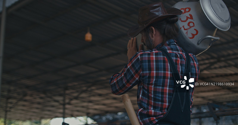 农民在奶牛棚里从桶中收集新鲜牛奶。图片素材