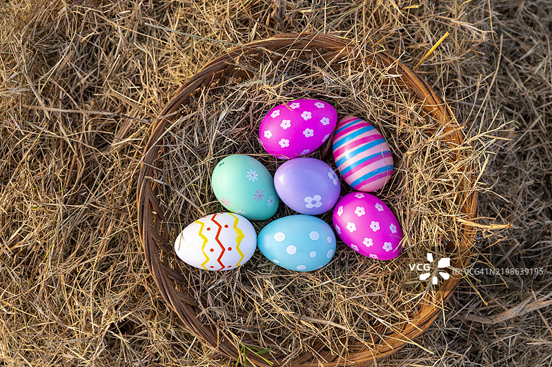 一个复活节彩蛋静静地躺在傍晚金色阳光下的草坪上。图片素材