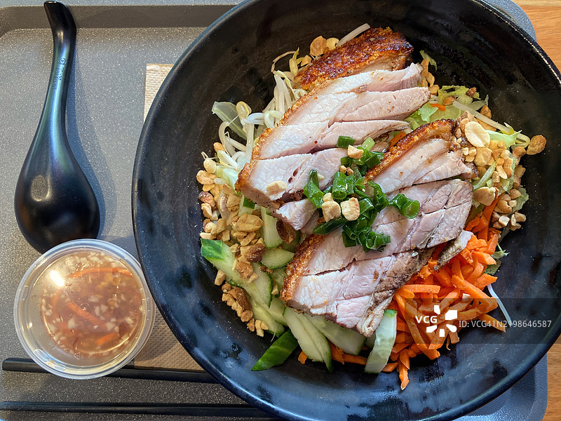 脆皮猪肉包（thịt heo quay bún）温暖的米粉沙拉，配有胡萝卜丝、生菜、黄瓜、花生、豆芽、香菜和鱼露酱。图片素材