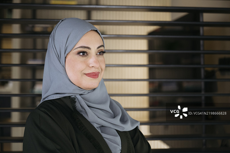 中年中东女性的头像，戴着头巾，微笑着望向一旁。图片素材