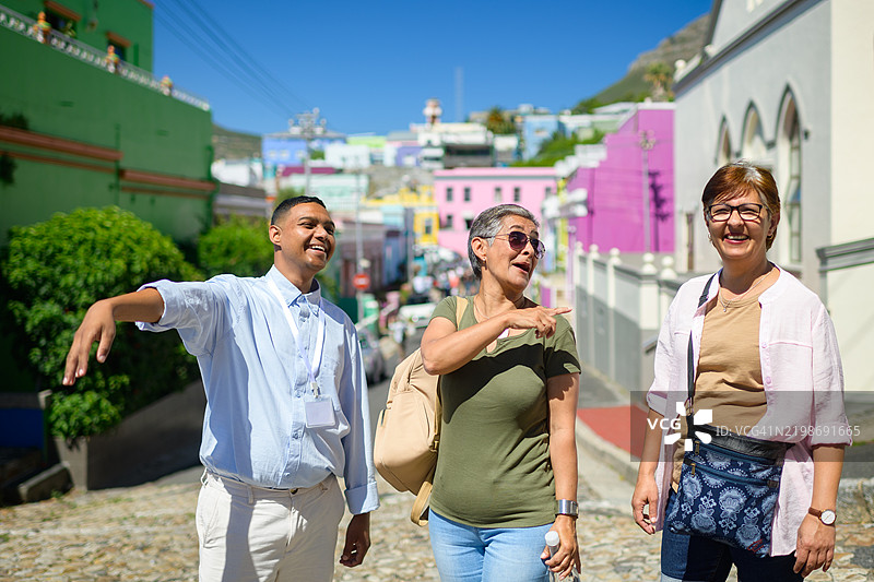 在开普博卡普马来区，笑着的年轻男导游与两位年长女性游客。图片素材