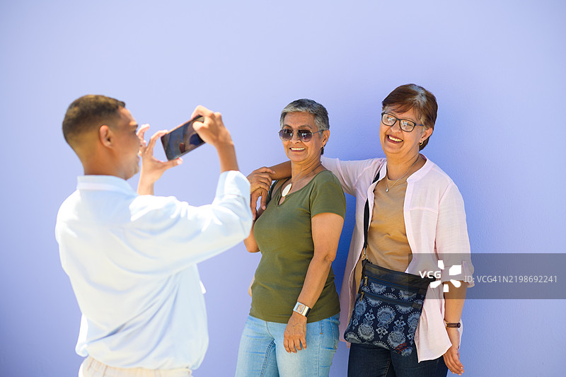 两位年长女性在浅紫色的丁香墙前摆姿势拍照图片素材